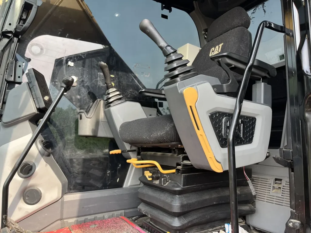 Used 2022 CAT 320GC excavator, operator seat, joysticks and monitor inside the cab
